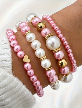 Pearl heart bracelet set on wrist with pink pearls and gold heart and bell charms