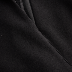 Black midi dress fabric close-up with diagonal seam and stitching