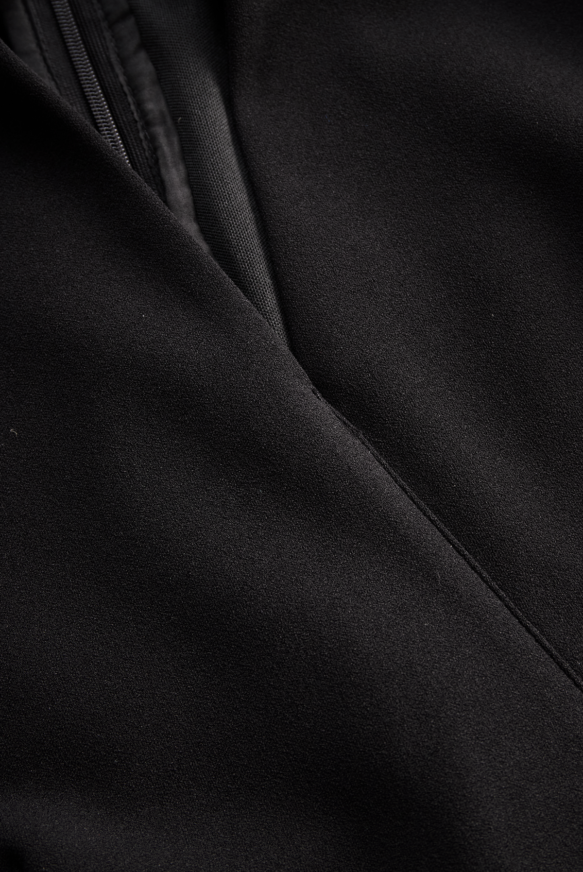 Black midi dress fabric close-up with diagonal seam and stitching