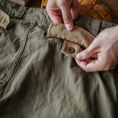 Close-up of army green trouser pocket flap with button and reinforced stitching