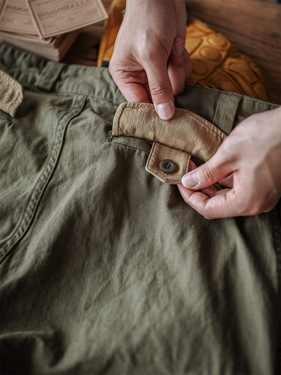 Close-up of army green trouser pocket flap with button and reinforced stitching