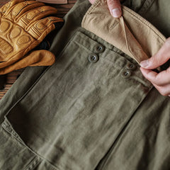 Army green M-47 HBT trousers with flap button pockets and reinforced seams
