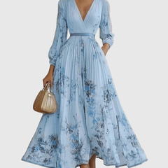 Light blue pleated maxi dress with V-neck, gathered waist and blue floral print, long sleeves.