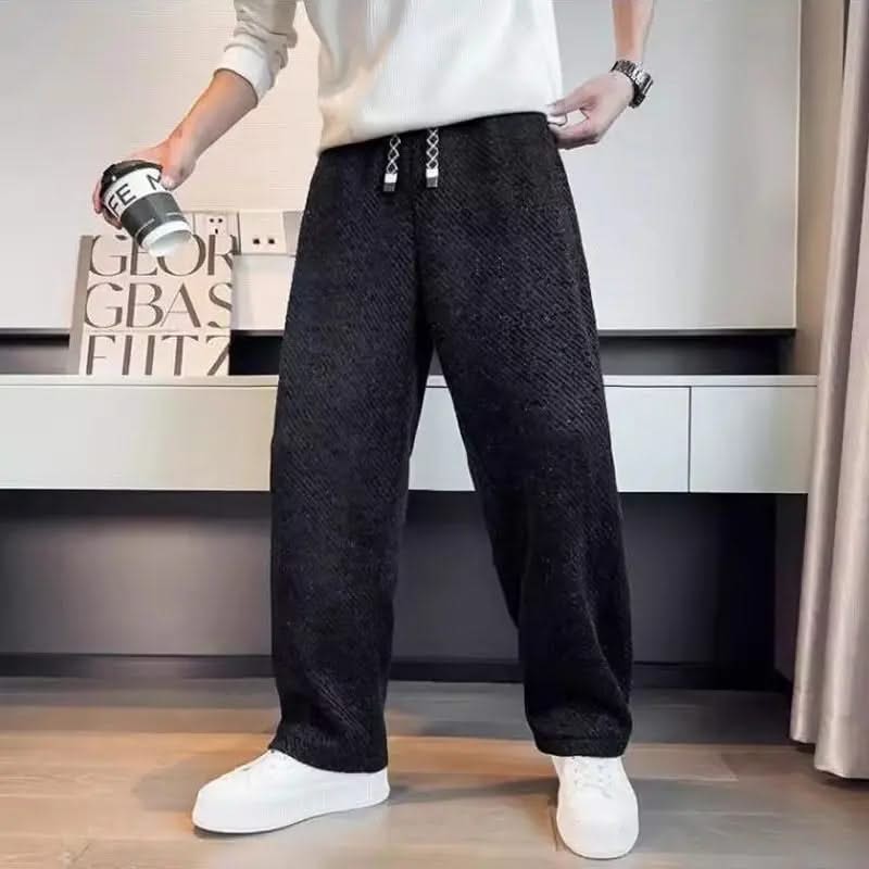 Black textured tapered pants with elastic waistband and drawstring ties