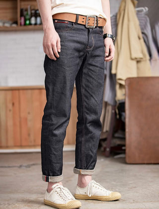Indigo denim jeans with dark wash, tan belt, cuffed hem and five-pocket design