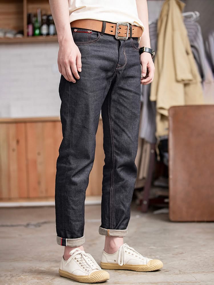 Indigo denim jeans with dark wash, tan belt, cuffed hem and five-pocket design