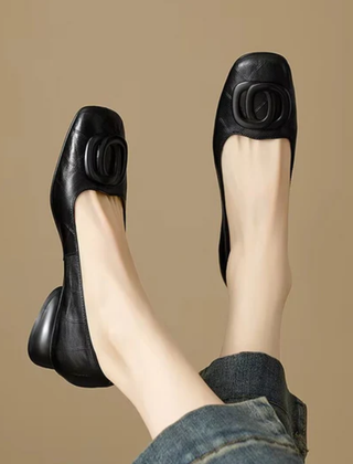 Black leather flats, side view with oval buckle ornament