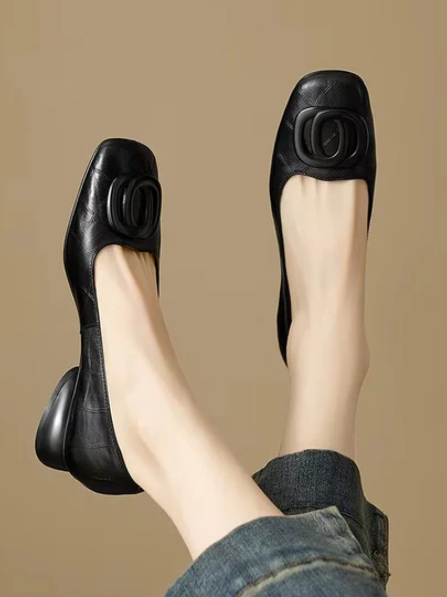 Black leather flats, side view with oval buckle ornament