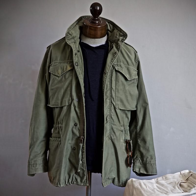 Green heritage jacket on mannequin with hood, drawstring waist, and flap pockets