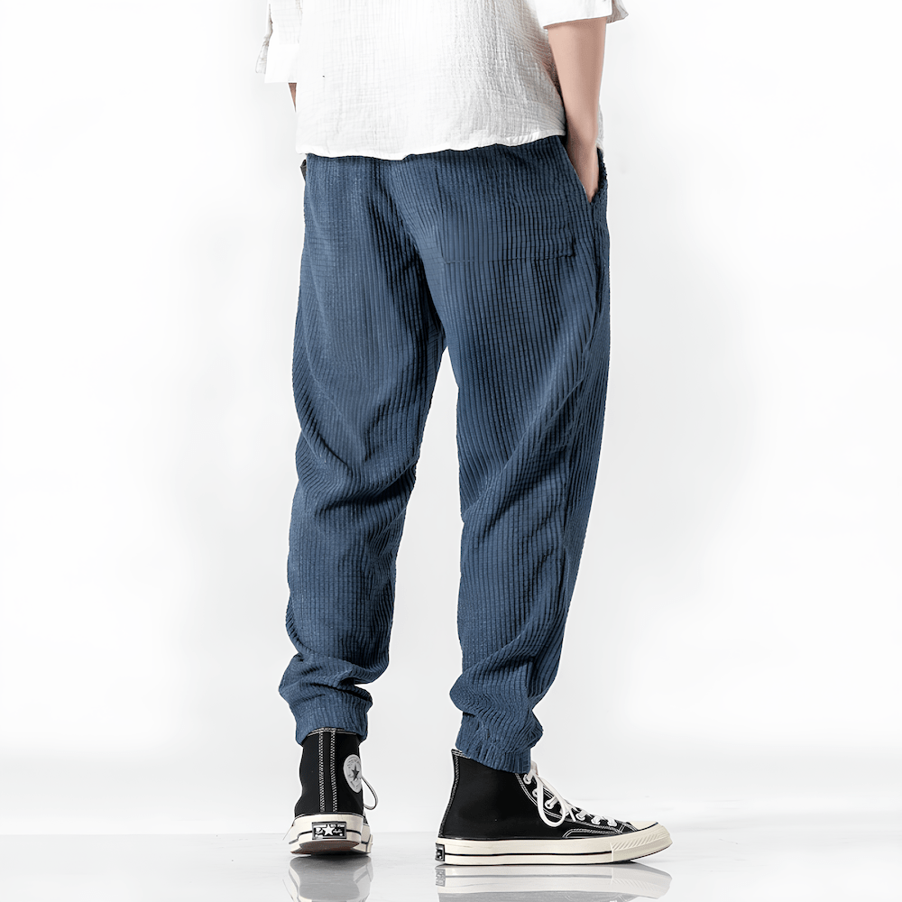 Blue ribbed velvet trousers with side pockets and tapered leg, elastic cuff hems