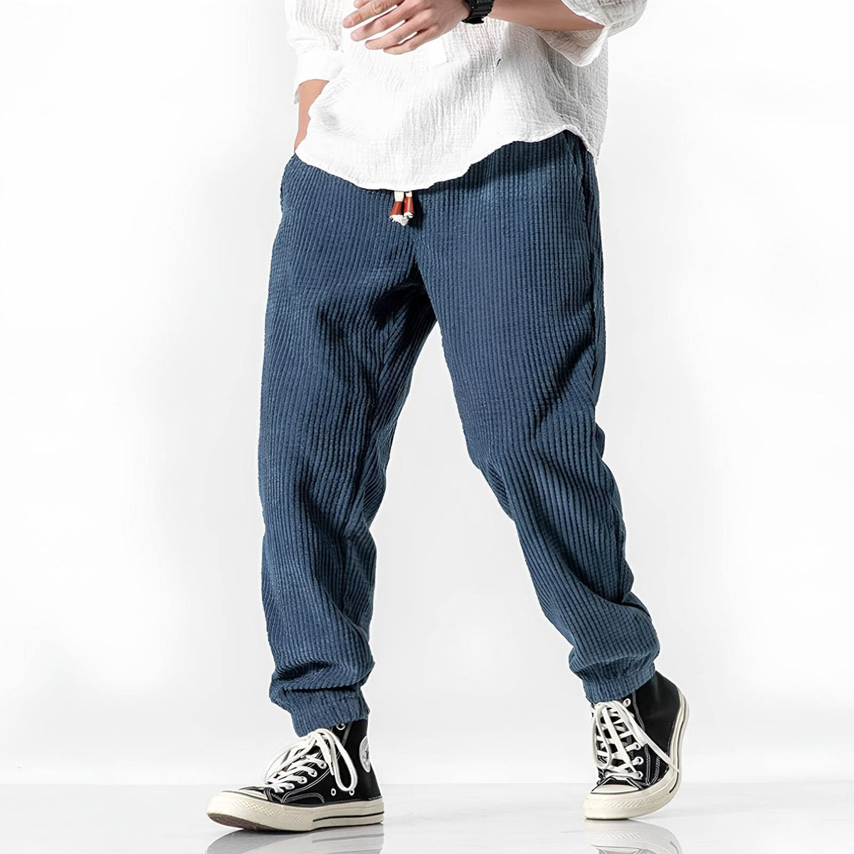 Blue ribbed velvet trousers with tapered legs, elastic cuffs, and drawstring waist