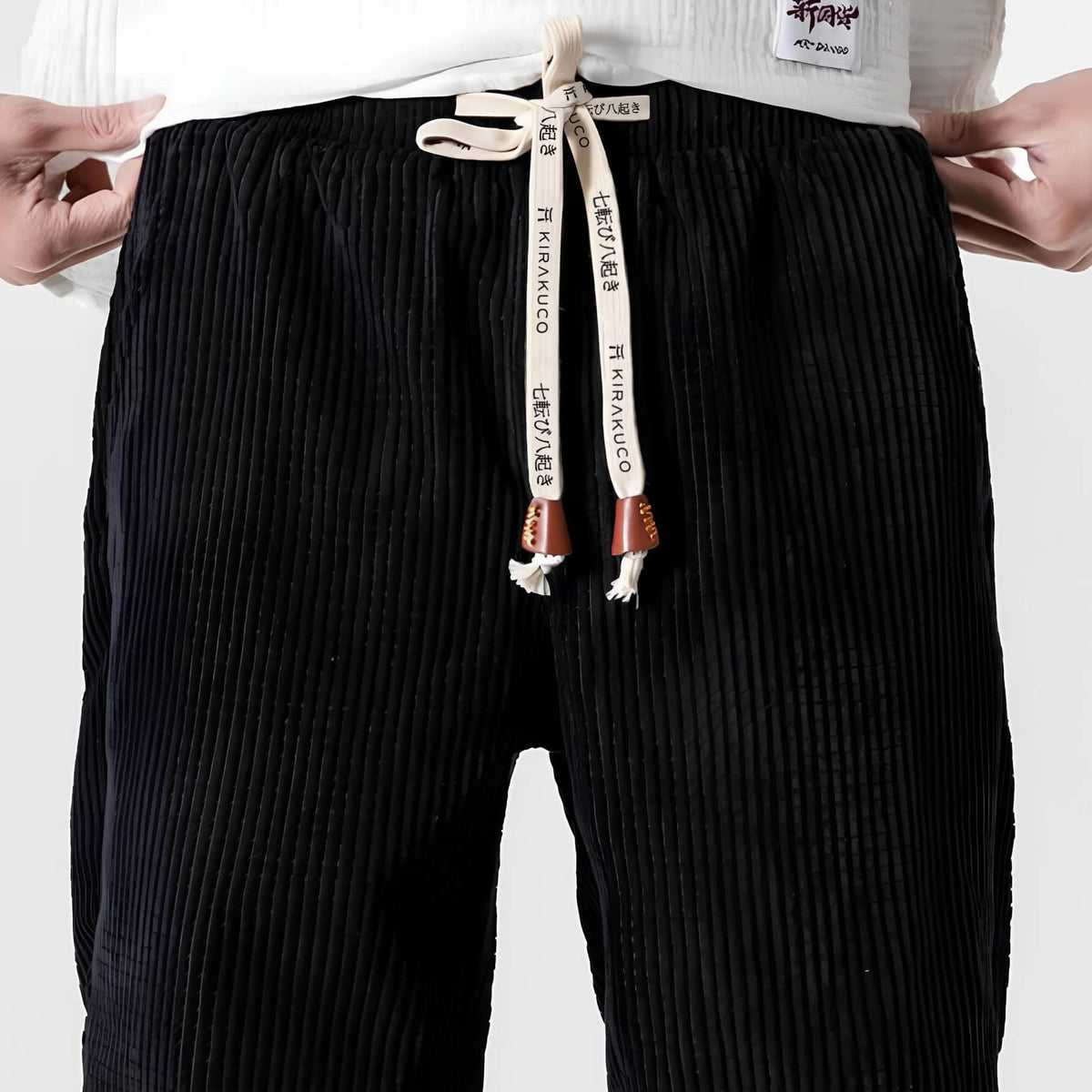 Black ribbed velvet trousers, elastic waistband, and drawstring with hanging tags