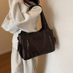 Dark brown leather shoulder handbag with top handles, front zippers, and side hanging strap
