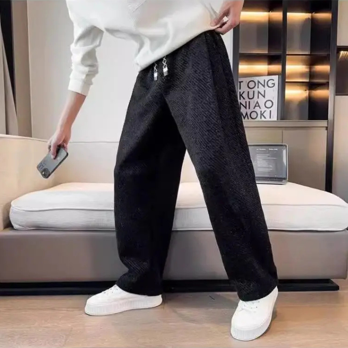 Black textured tapered pants with elastic waistband and drawstring ties