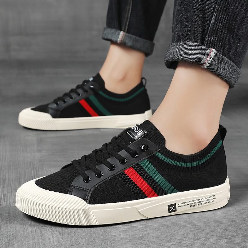 Black knit sneakers on feet with multicolor side stripe and lace-up front