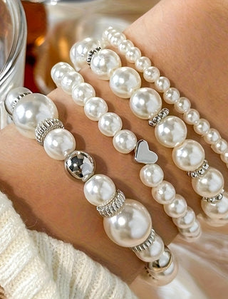 Pearl heart bracelet set close-up with white pearls, gold and silver charms, heart link