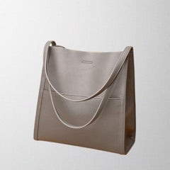 Gray vegan leather shoulder bag with curved strap accent and side panel stitching