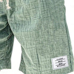 Green everyday shorts close-up with brand patch and stitched side seam detail