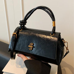 Black leather-look crossbody shoulder bag with gold-tone clasp and top flap