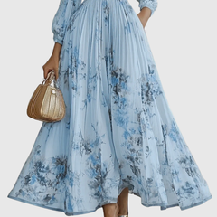 Light blue pleated maxi skirt with vertical pleats and blue floral print, long sleeves.