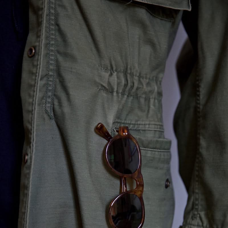 Green jacket close-up: snap buttons, flap chest pocket, and adjustable waist