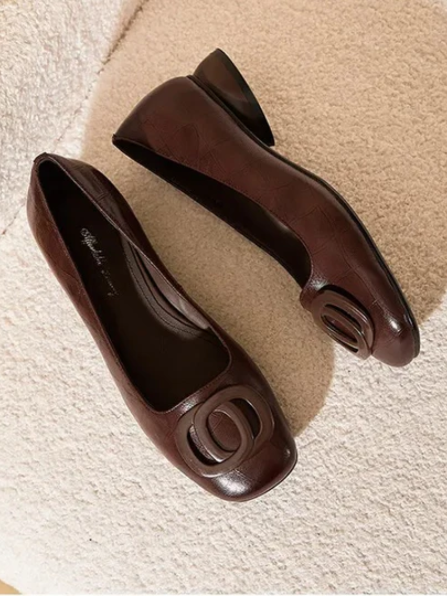 Brown leather flats with oval buckle hardware, top view