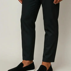 Black slip-on suede loafer worn with dark trousers