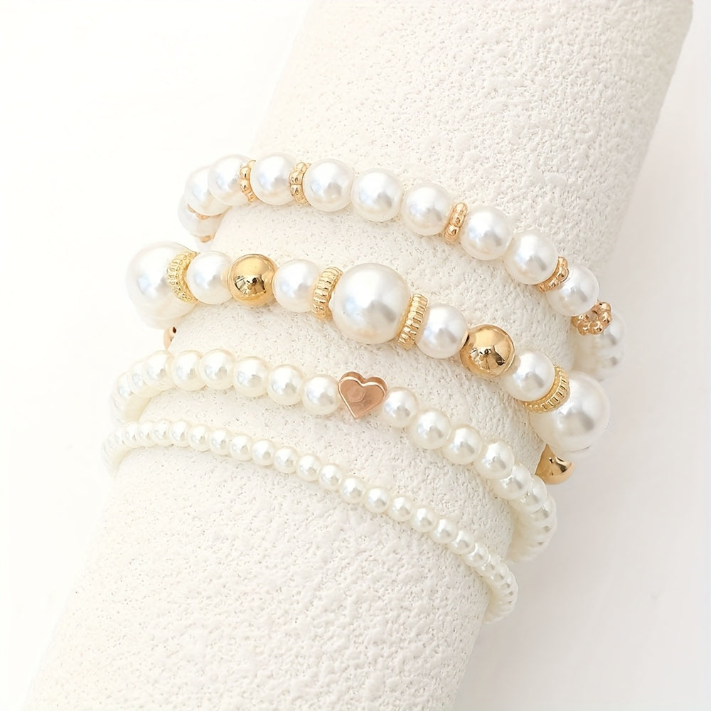 Pearl heart bracelet set display on light fabric with white pearls and gold heart charms