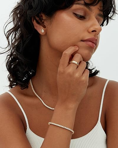 Gold-tone tennis bracelet with round stones on arm
