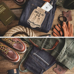 Indigo denim jeans with patch label and belt loops, laid out with leather accessories