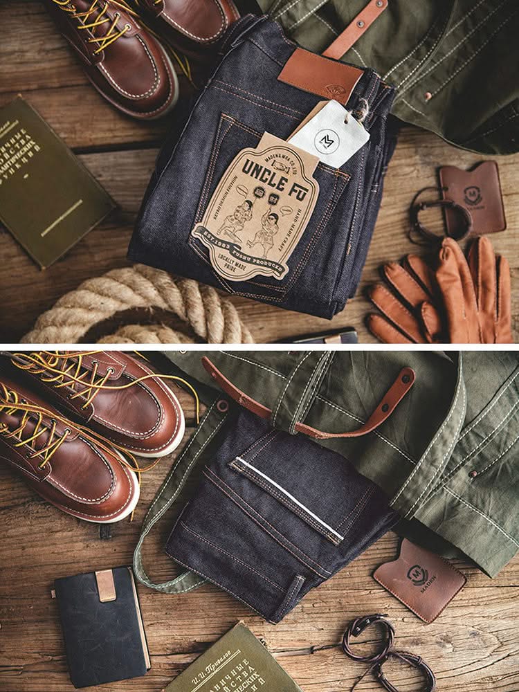 Indigo denim jeans with patch label and belt loops, laid out with leather accessories
