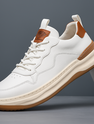 White leather low-top sneaker with lace-up front, orange-brown heel and cream sole