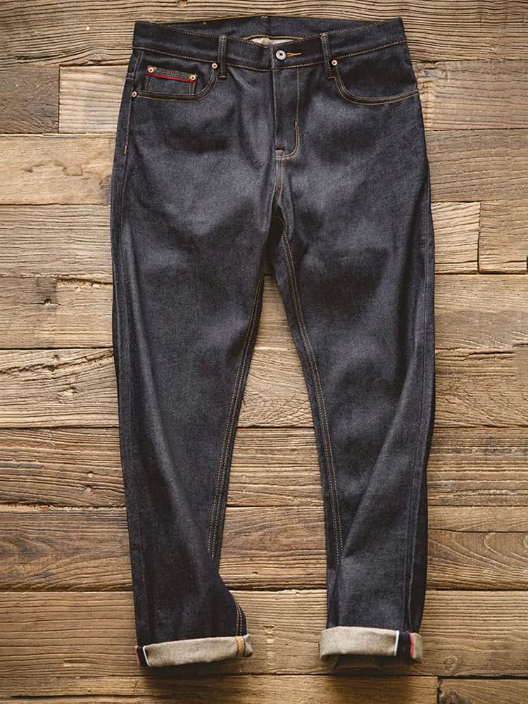 Indigo denim jeans on wood floor, dark wash with button fly and stitched pockets