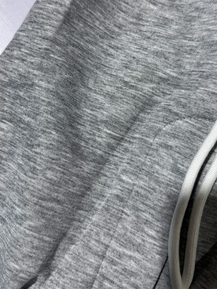 Heather grey trouser fabric detail with stitched hem and drawstring cord