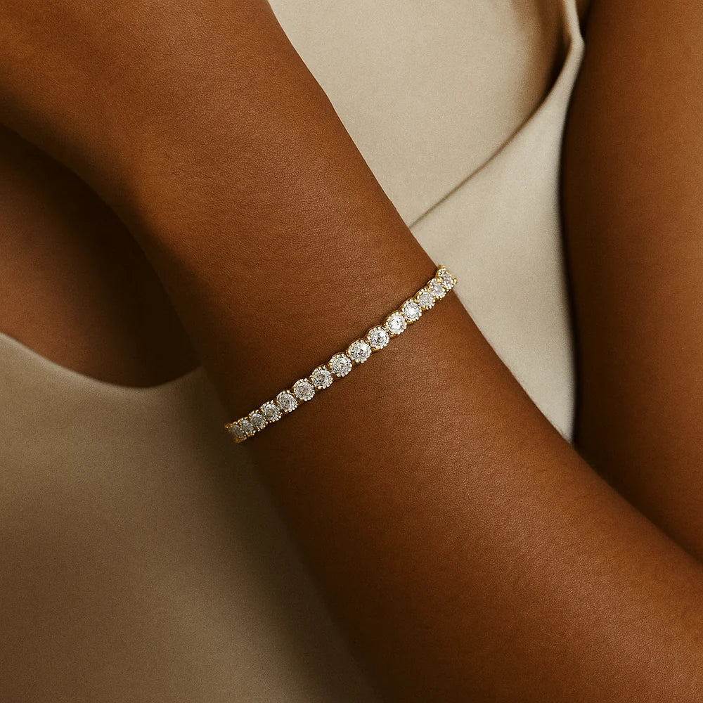 Gold-tone tennis bracelet with micro-set round stones, close-up on arm