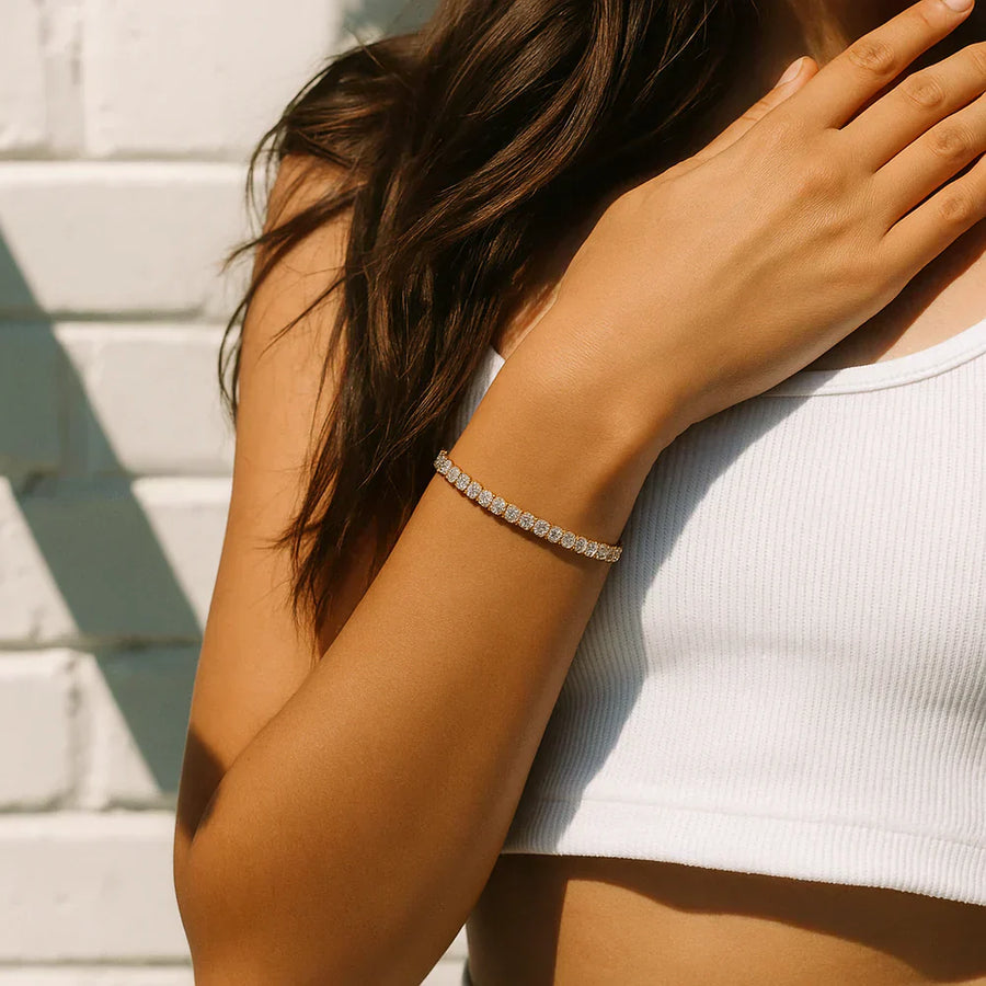 Gold-tone tennis bracelet with a row of round stones on wrist
