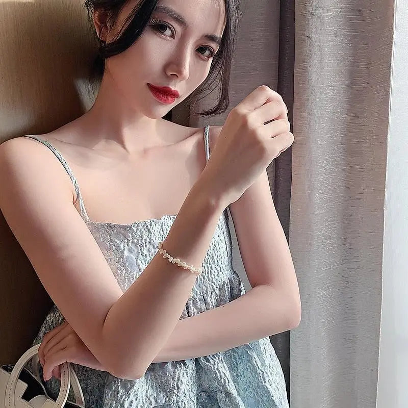 Pearl bracelet worn on arm with delicate gold-tone chain