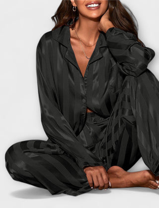 Black satin casual set with button-front shirt and wide-leg striped pants, seated