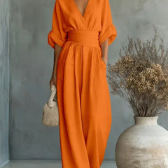 Orange V-neck high-waisted jumpsuit with gathered waist and loose wide-leg silhouette