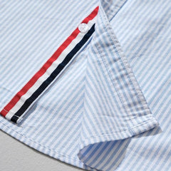 Blue striped linen shirt detail showing side placket trim and stitched pocket edge