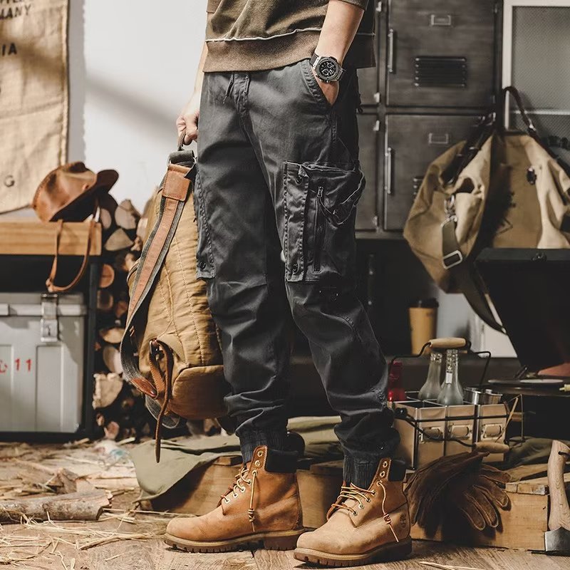 Black utility trousers with cargo pockets, drawstring waist, and button-flap details