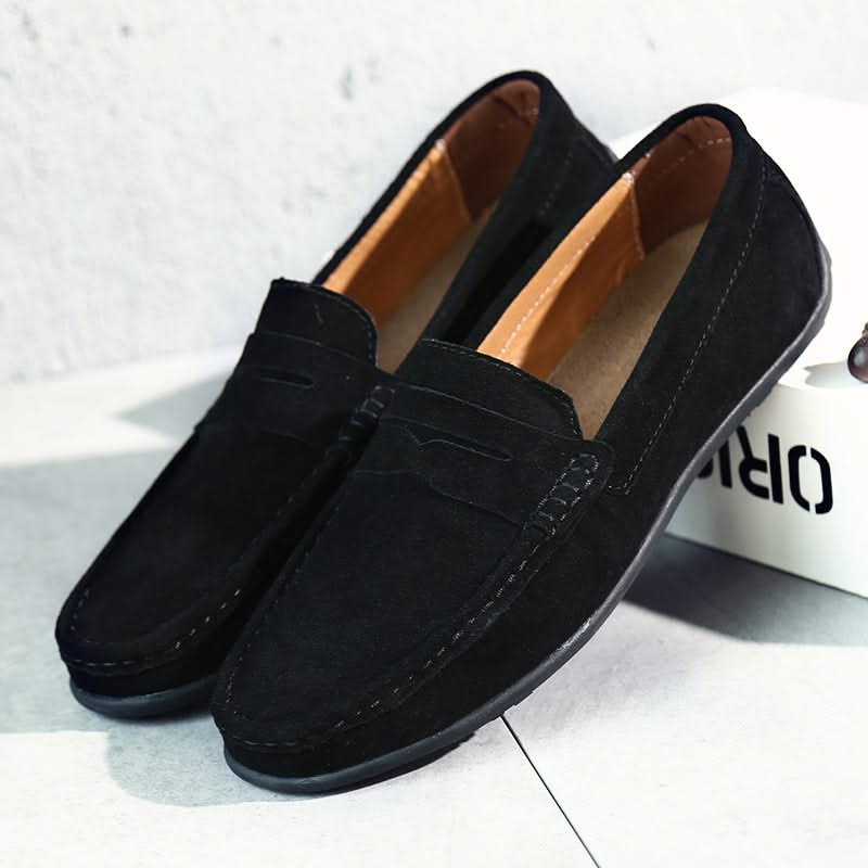 Suede loafers in black with slip-on strap detail, stitched moc toe, and rubber sole