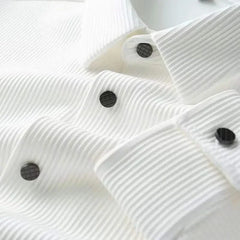 White business shirt front, close-up of textured fabric and black button details