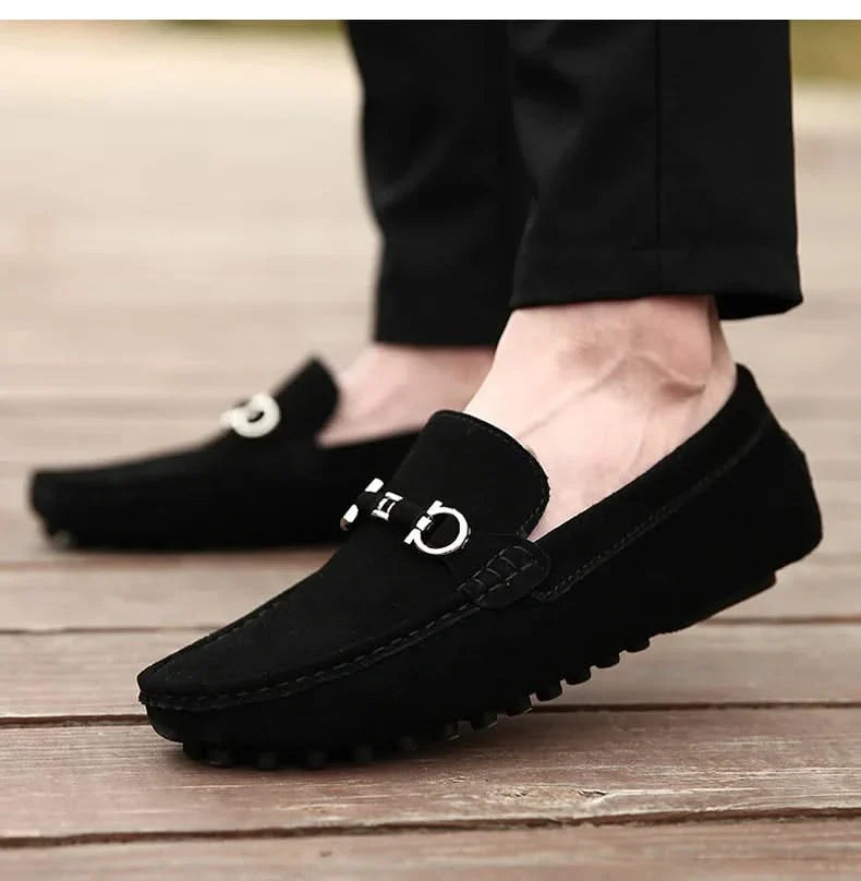 Black suede loafers with silver buckle hardware and textured rubber outsole