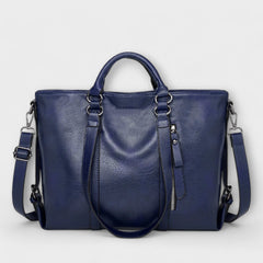 Blue leather handbag with top handles, shoulder straps, and zip pocket detail