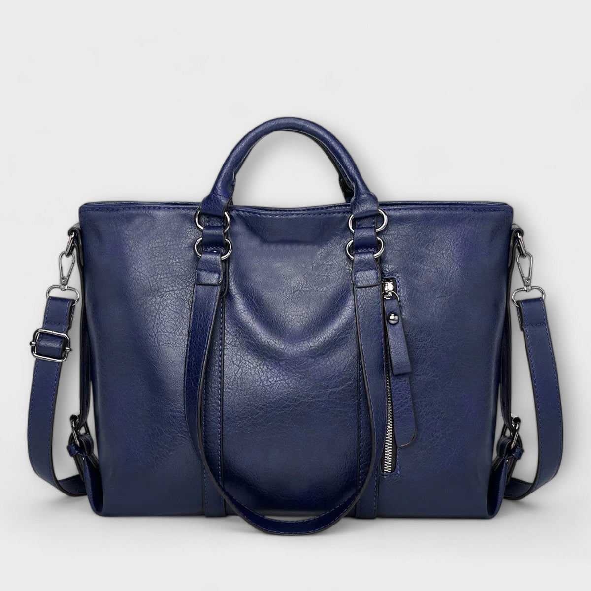 Blue leather handbag with top handles, shoulder straps, and zip pocket detail