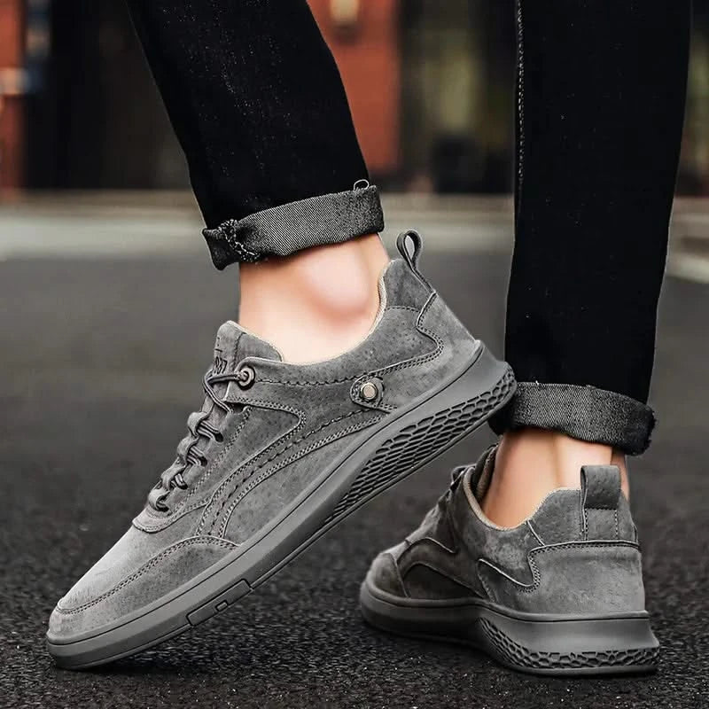 Grey suede lace-up sneakers with textured side panel and rubber sole, on feet