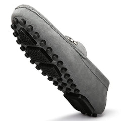 Gray suede loafer showing treaded rubber sole and buckle strap detail