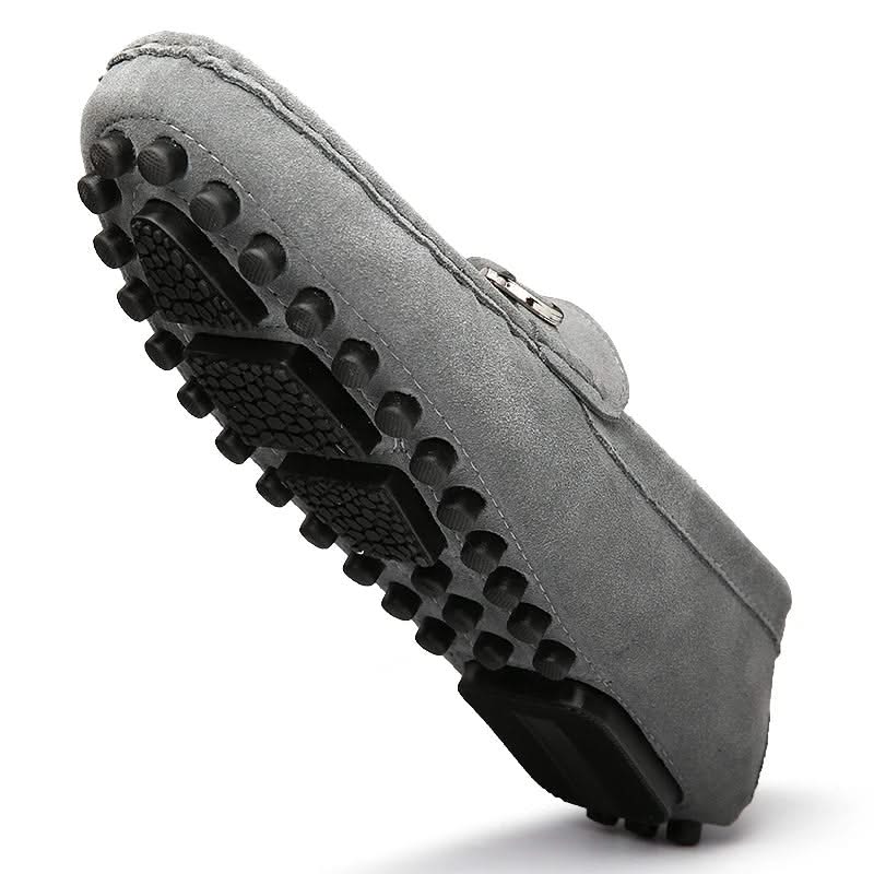 Gray suede loafer showing treaded rubber sole and buckle strap detail