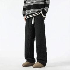 Black quilted pants with raised oval texture and drawstring waist, relaxed fit.